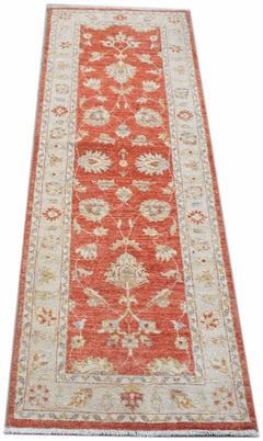 A handmade Afghan Chobi runner rug featuring a traditional floral pattern in terracotta and cream.