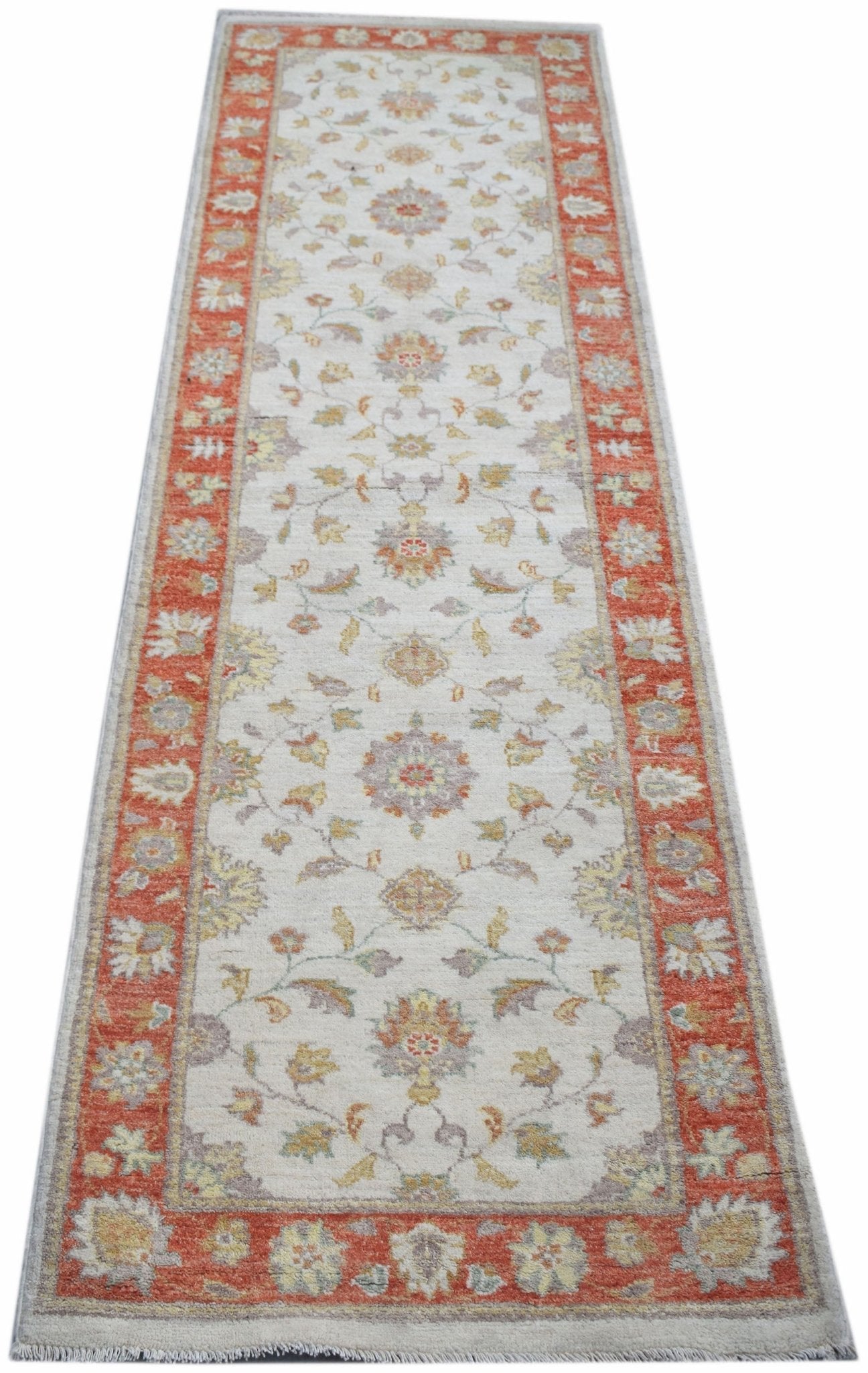 A handmade Afghan Chobi runner rug featuring a traditional floral pattern in orange and cream.