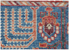 A close-up of an Afghan Chobi runner featuring intricate geometric patterns in blue and red wool.