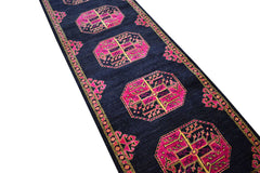 A handmade Afghan Chobi runner rug featuring pink and gold geometric motifs on a dark blue field.