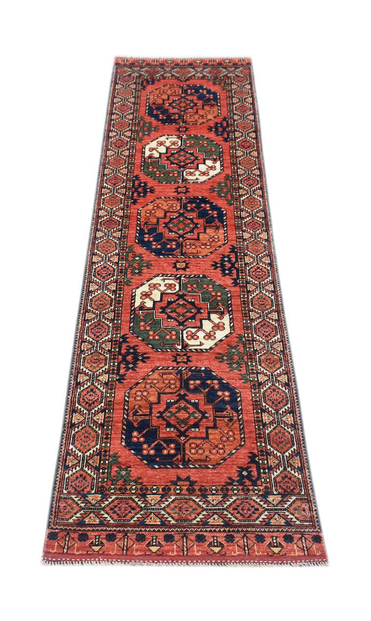 A handmade Afghan Chobi runner rug featuring geometric octagonal motifs in red, blue, and green.