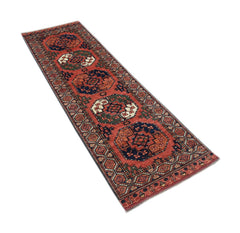 An Afghan Chobi runner rug featuring geometric medallions in red, blue, and green wool.