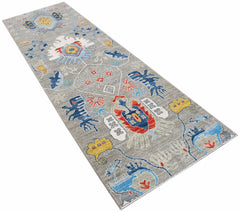 A handwoven Afghan Chobi runner rug featuring a grey field with colorful traditional motifs.
