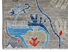 A close-up of a handwoven Afghan Chobi runner featuring blue and red floral motifs on a grey base.