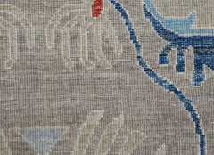 A close-up of a handwoven Afghan Chobi runner featuring intricate blue and red floral patterns.