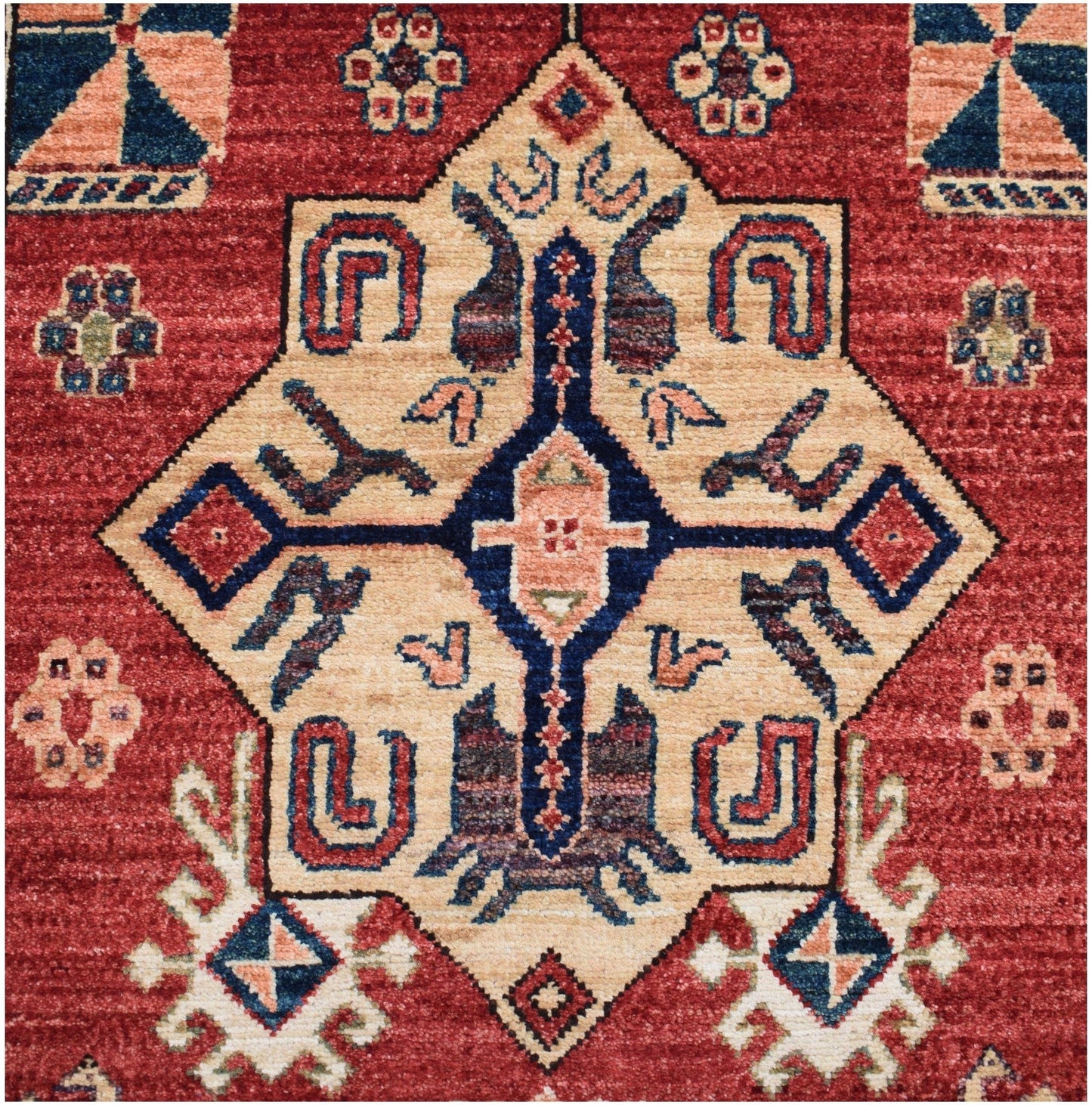 Handmade Afghan Chobi runner featuring a geometric diamond medallion on a red wool background.