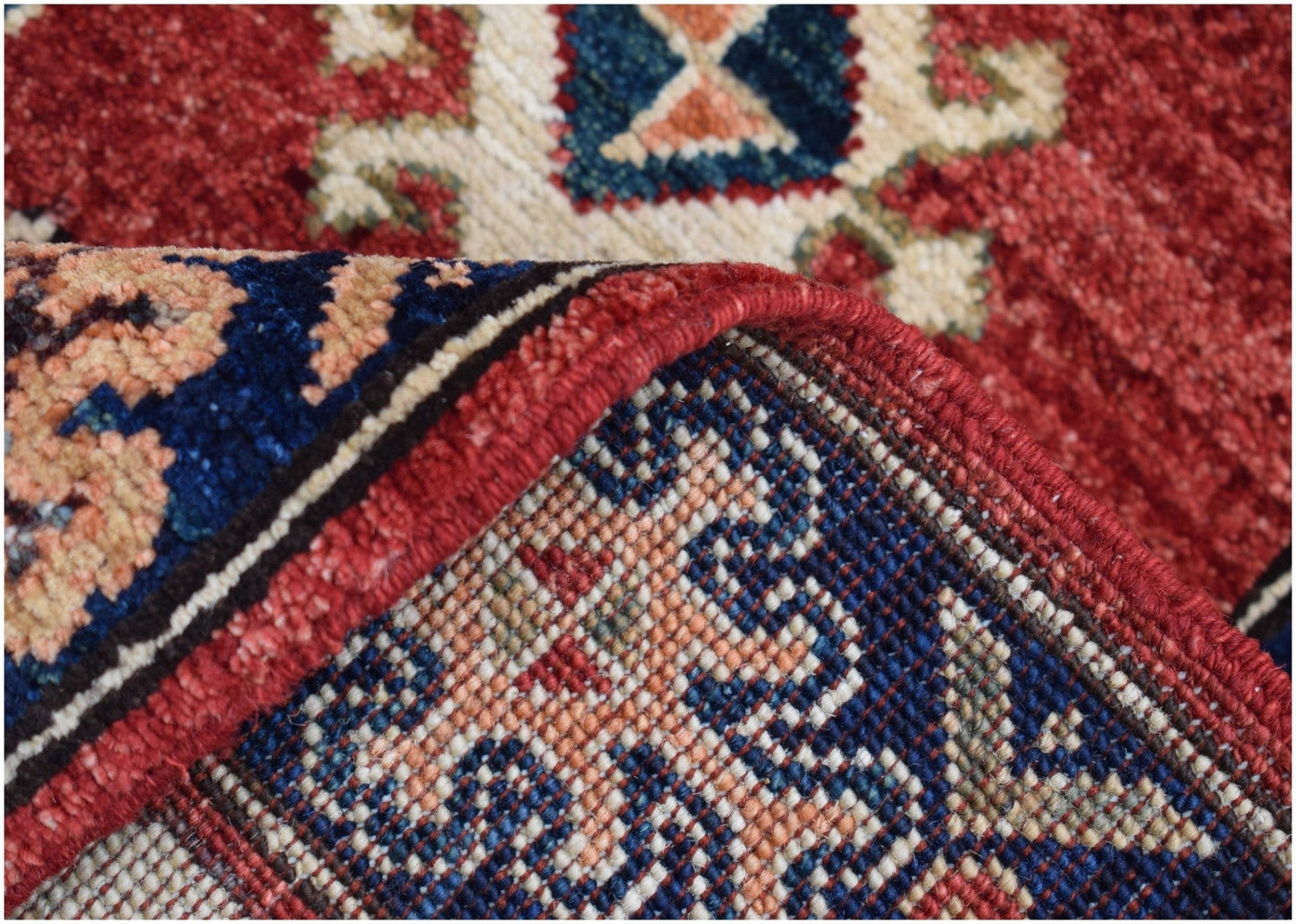 A close-up of a handmade Afghan Chobi runner showing its red, blue, and cream patterned weave.