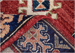 A close-up of a handmade Afghan Chobi runner showing its red, blue, and cream patterned weave.
