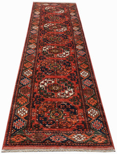 A handmade Afghan Chobi runner rug featuring traditional geometric patterns in red and blue tones.