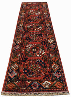 A handwoven Afghan Chobi runner rug featuring geometric medallions in red, blue, and cream tones.