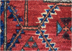 A close-up of an Afghan Chobi runner featuring intricate geometric patterns in red, blue, and cream.