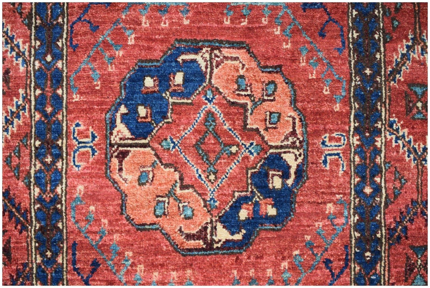 An Afghan Chobi runner featuring a central geometric medallion in blue and peach on a red field.