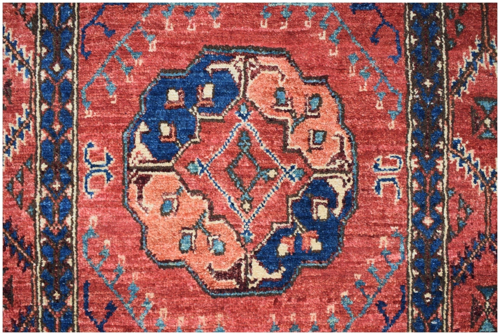 An Afghan Chobi runner featuring a central geometric medallion in blue and peach on a red field.