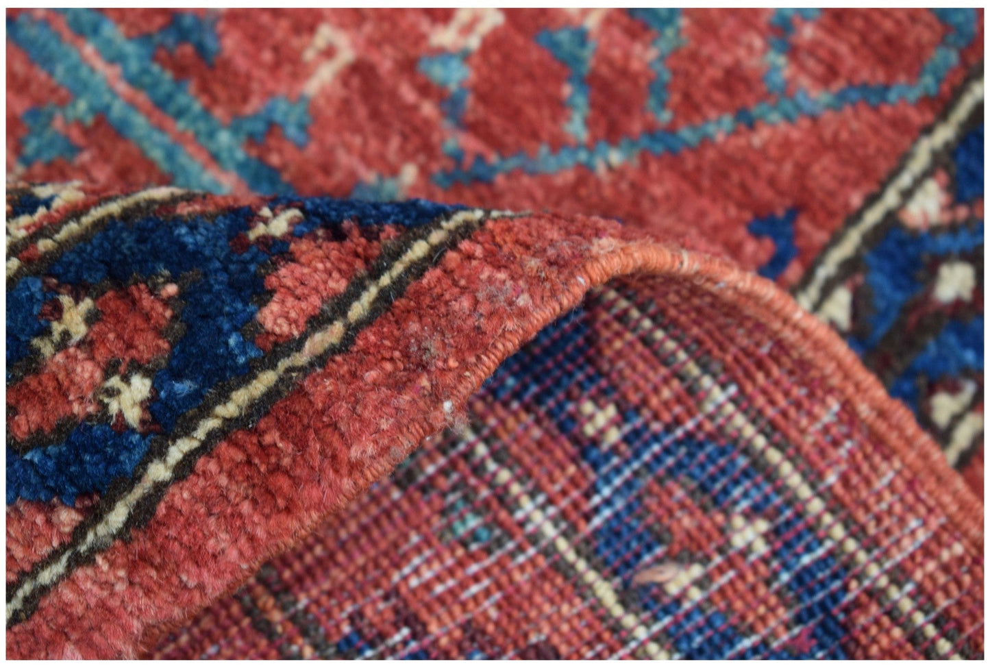 A handmade Afghan Chobi runner featuring a traditional red and blue patterned wool pile.