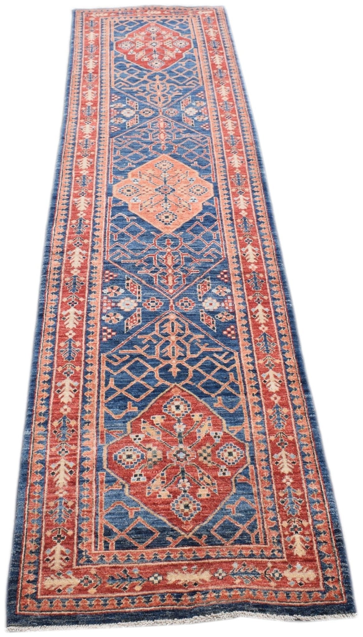 Handmade Afghan Chobi runner rug featuring traditional geometric patterns in blue and terracotta.