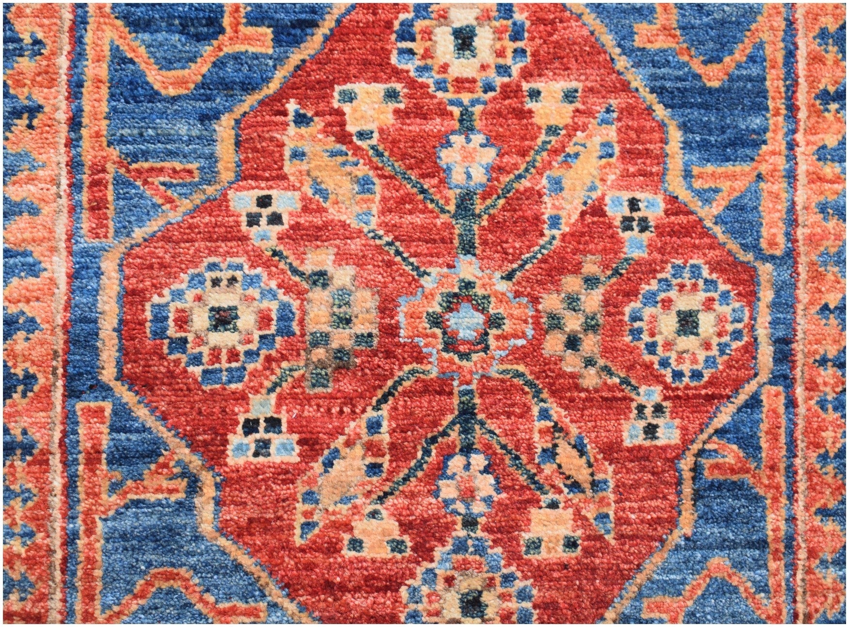 An Afghan Chobi runner featuring a traditional red diamond medallion pattern on a blue background.