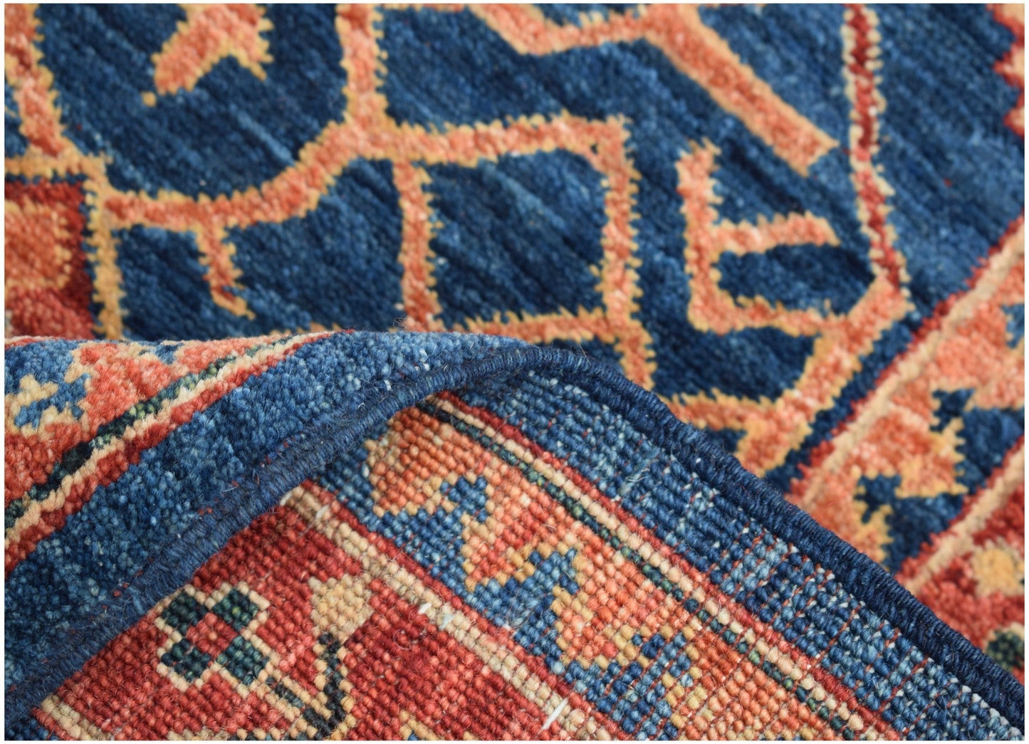 A close-up of a handmade Afghan Chobi runner featuring a blue and orange geometric pattern.