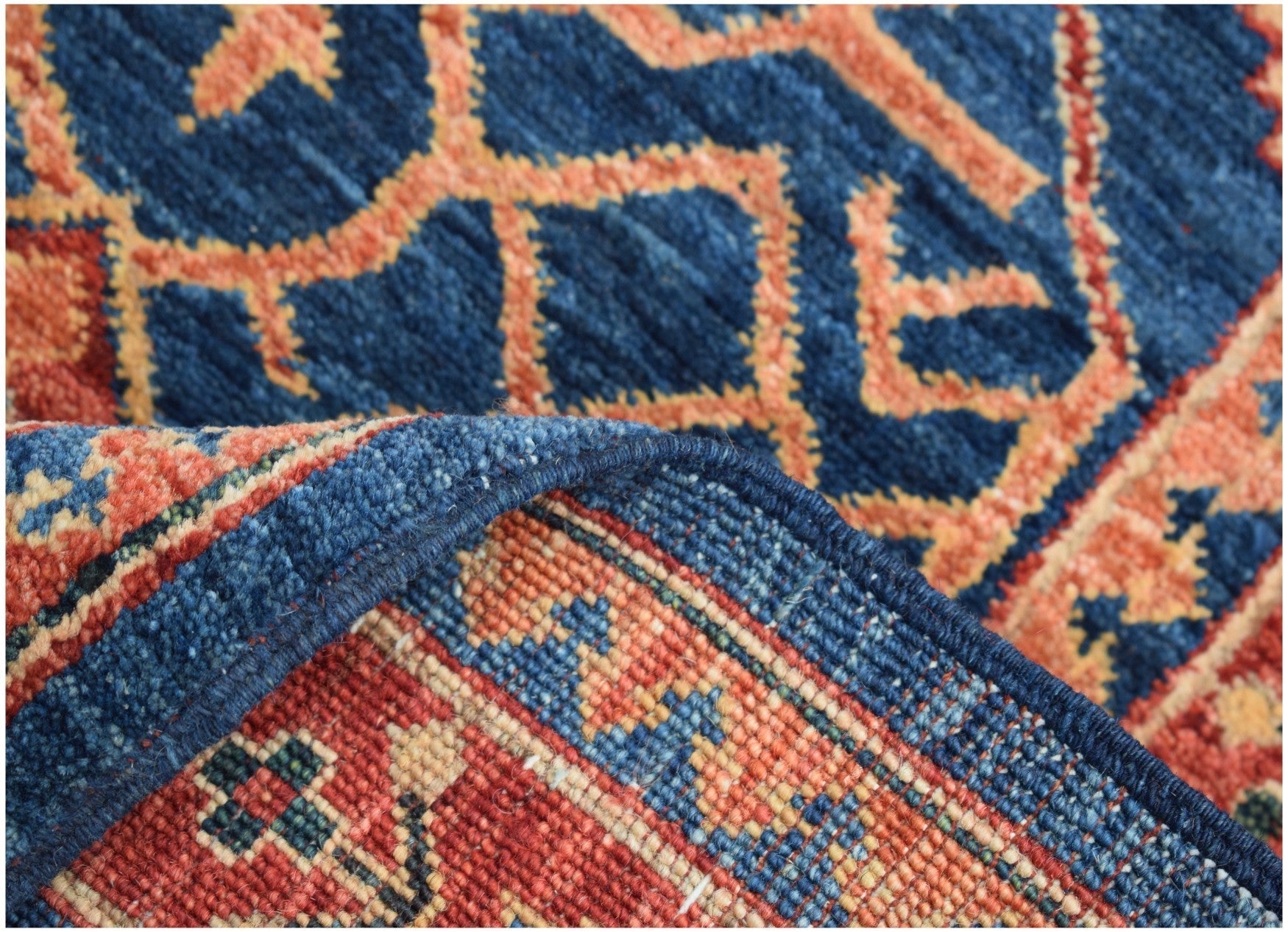 A close-up of a handmade Afghan Chobi runner featuring a blue and orange geometric pattern.