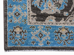A close-up of an Afghan Chobi runner featuring intricate floral patterns in blue, grey, and black.