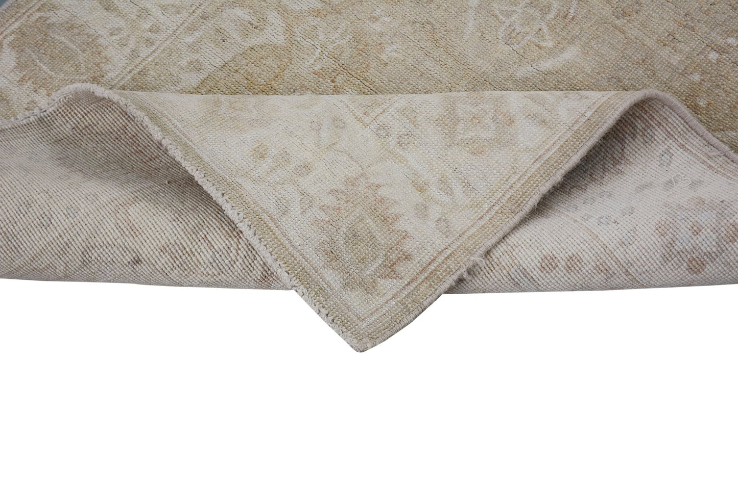 A corner of a handmade Afghan Chobi runner with a neutral, wood-toned traditional pattern.