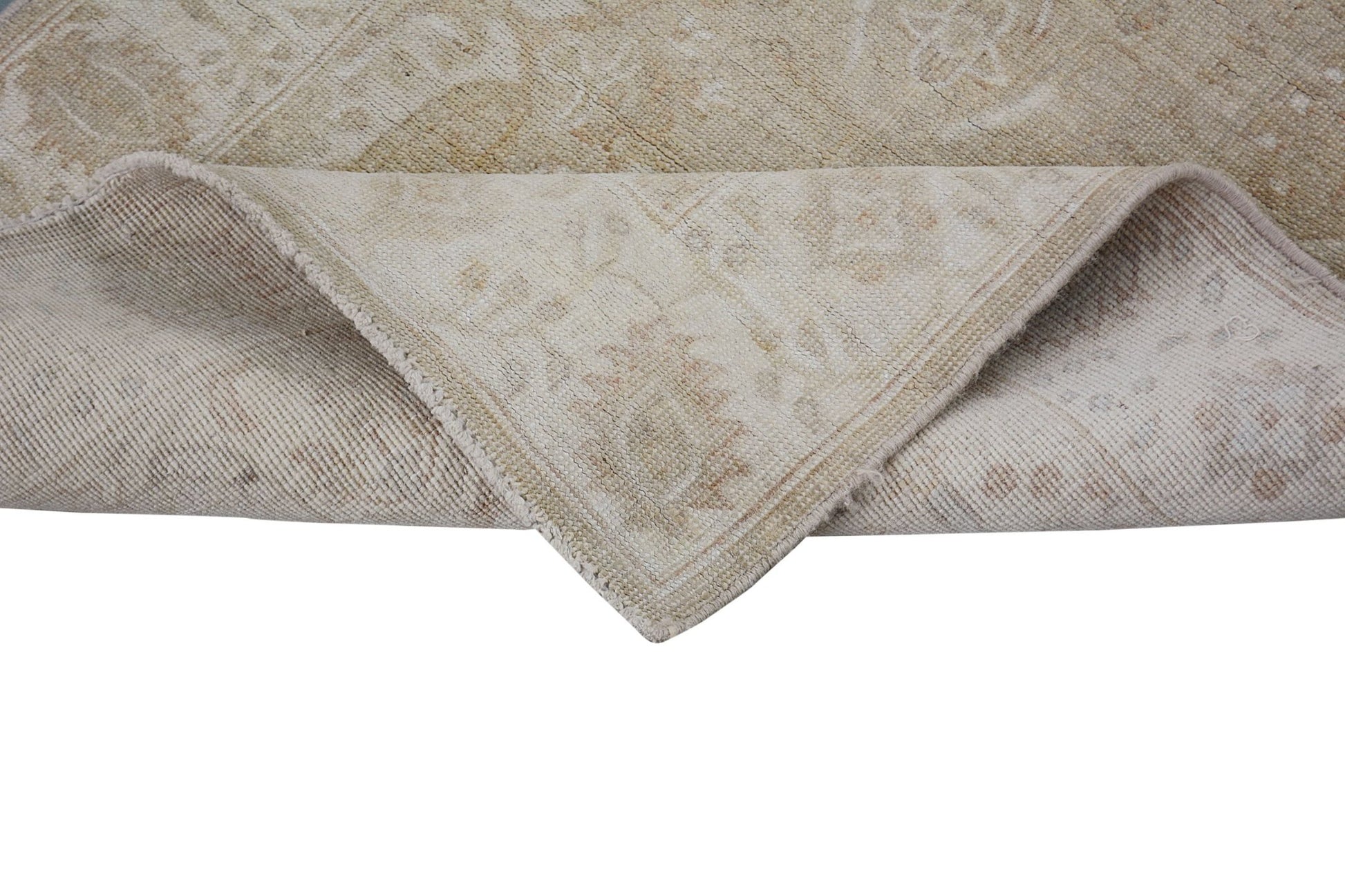 A corner of a handmade Afghan Chobi runner with a neutral, wood-toned traditional pattern.