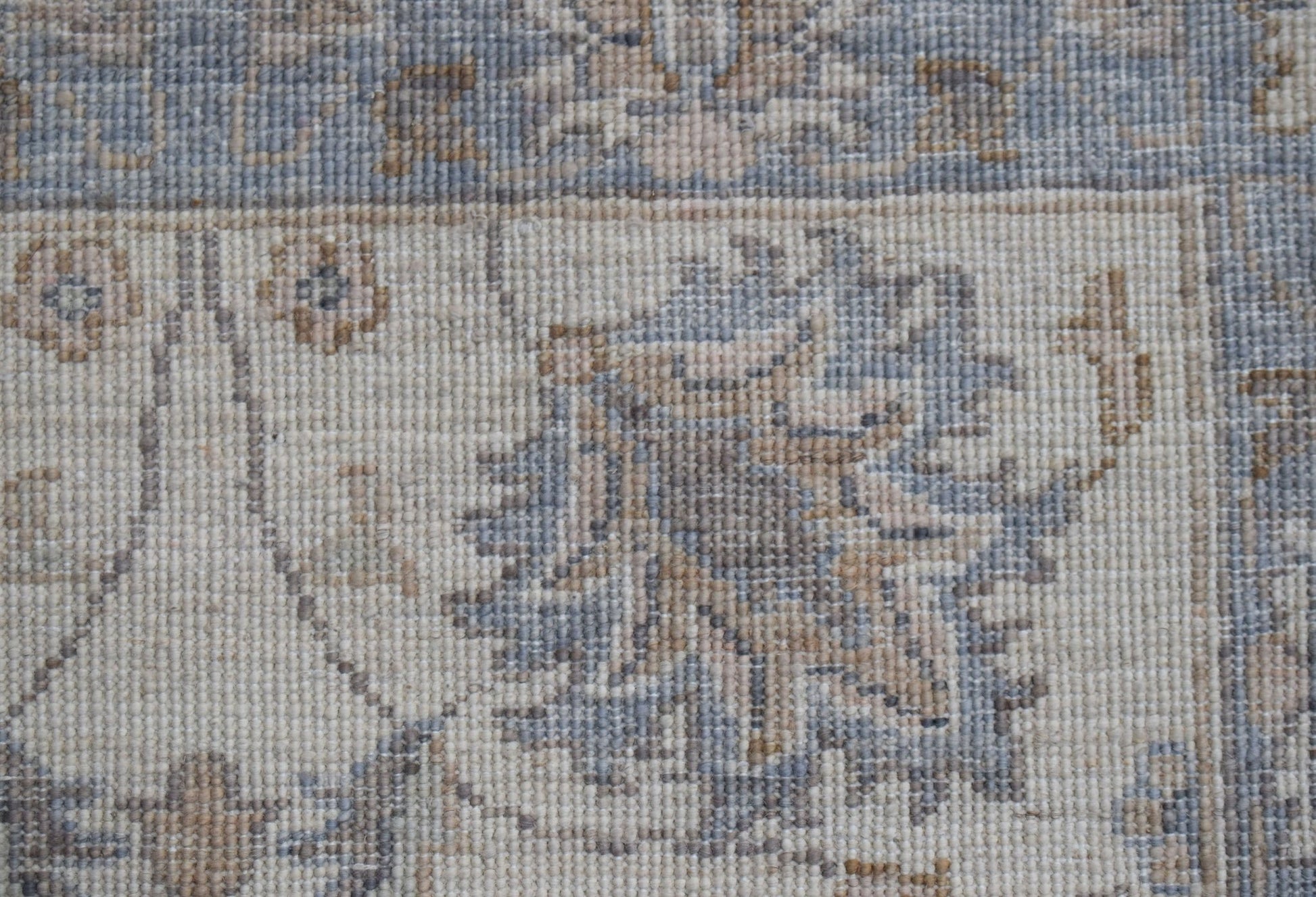 A close-up of an Afghan Chobi runner featuring intricate floral patterns in muted blue and tan tones.