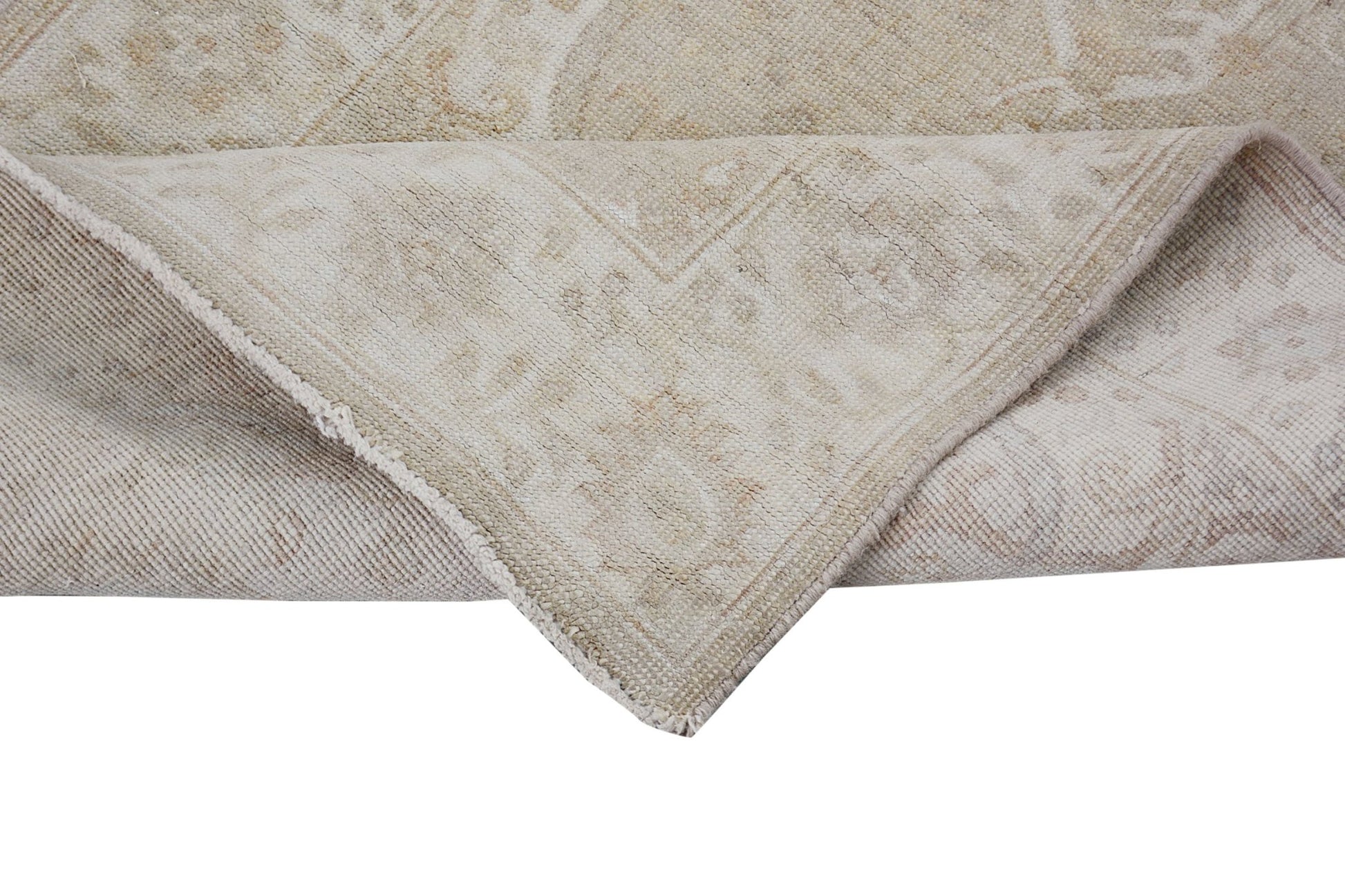 A corner of a handmade Afghan Chobi runner featuring a neutral beige pattern on wool.