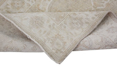 A corner of a handmade Afghan Chobi runner featuring a neutral beige pattern on wool.