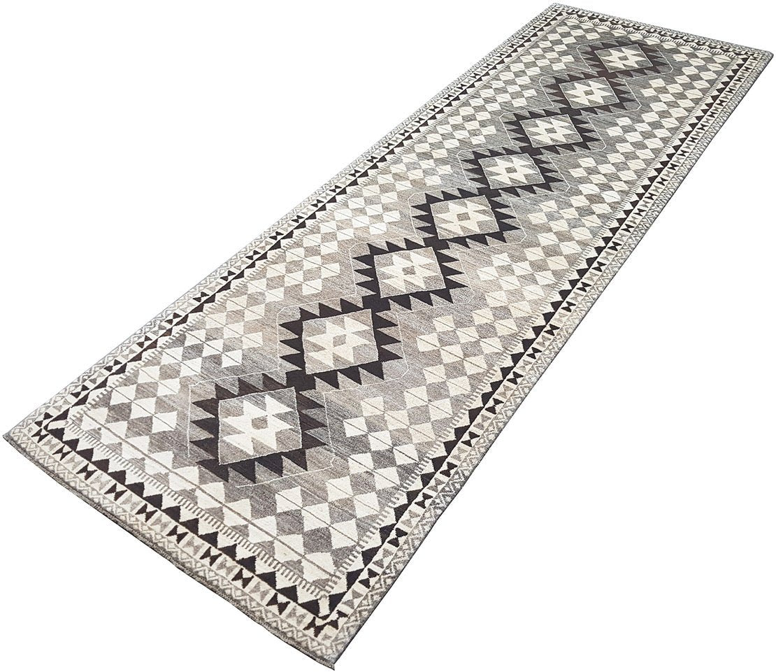 A handmade Afghan Chobi runner rug featuring a geometric diamond pattern in shades of grey and cream.