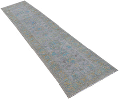 A handwoven transitional Oushak runner rug featuring a floral pattern in blue and gold on a grey base.