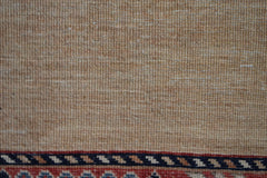 A close-up of a handwoven Afghan Chobi runner featuring a textured beige field and a patterned border.