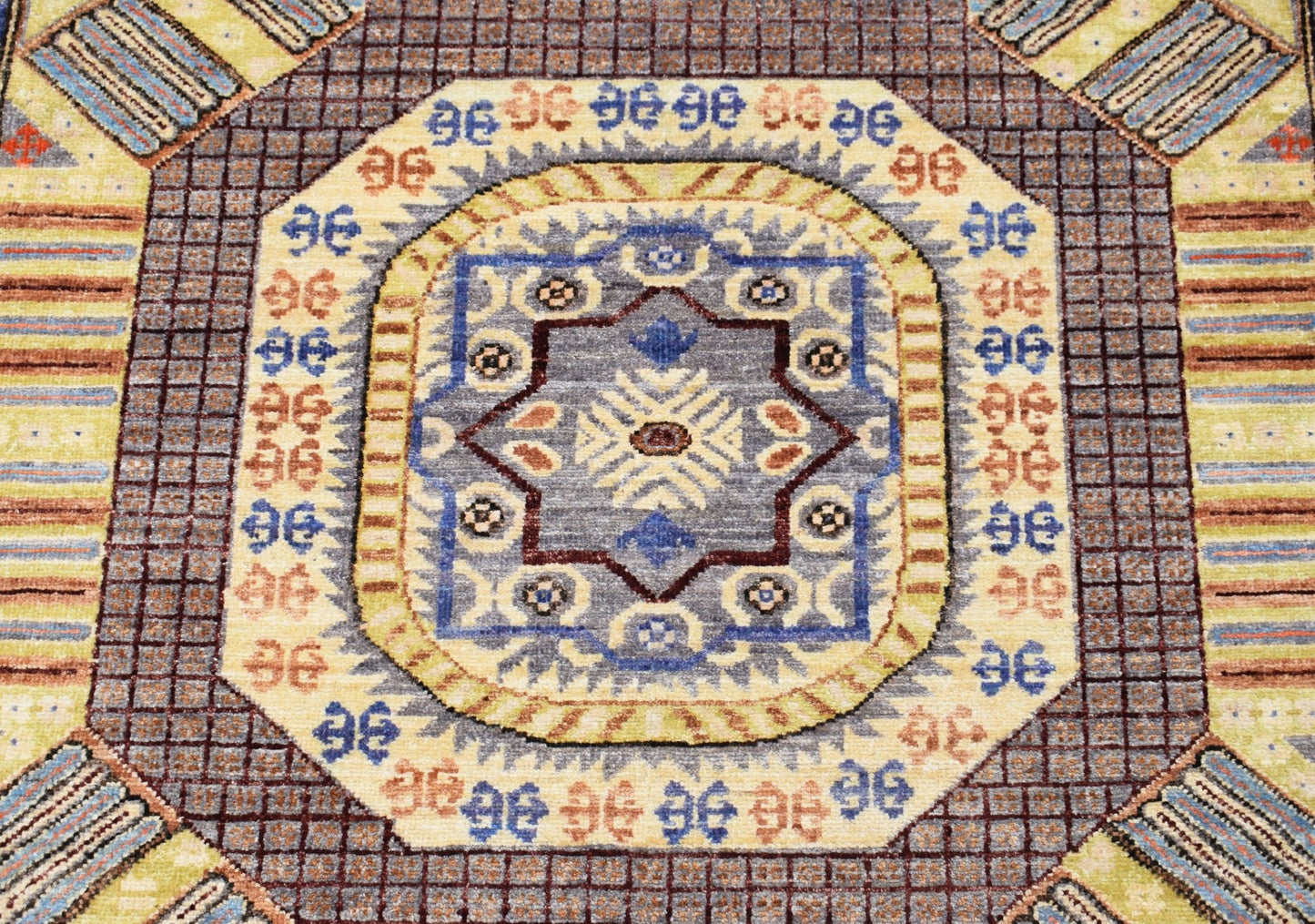 A handmade Afghan Chobi runner featuring a central geometric medallion in blue and earthy tones.