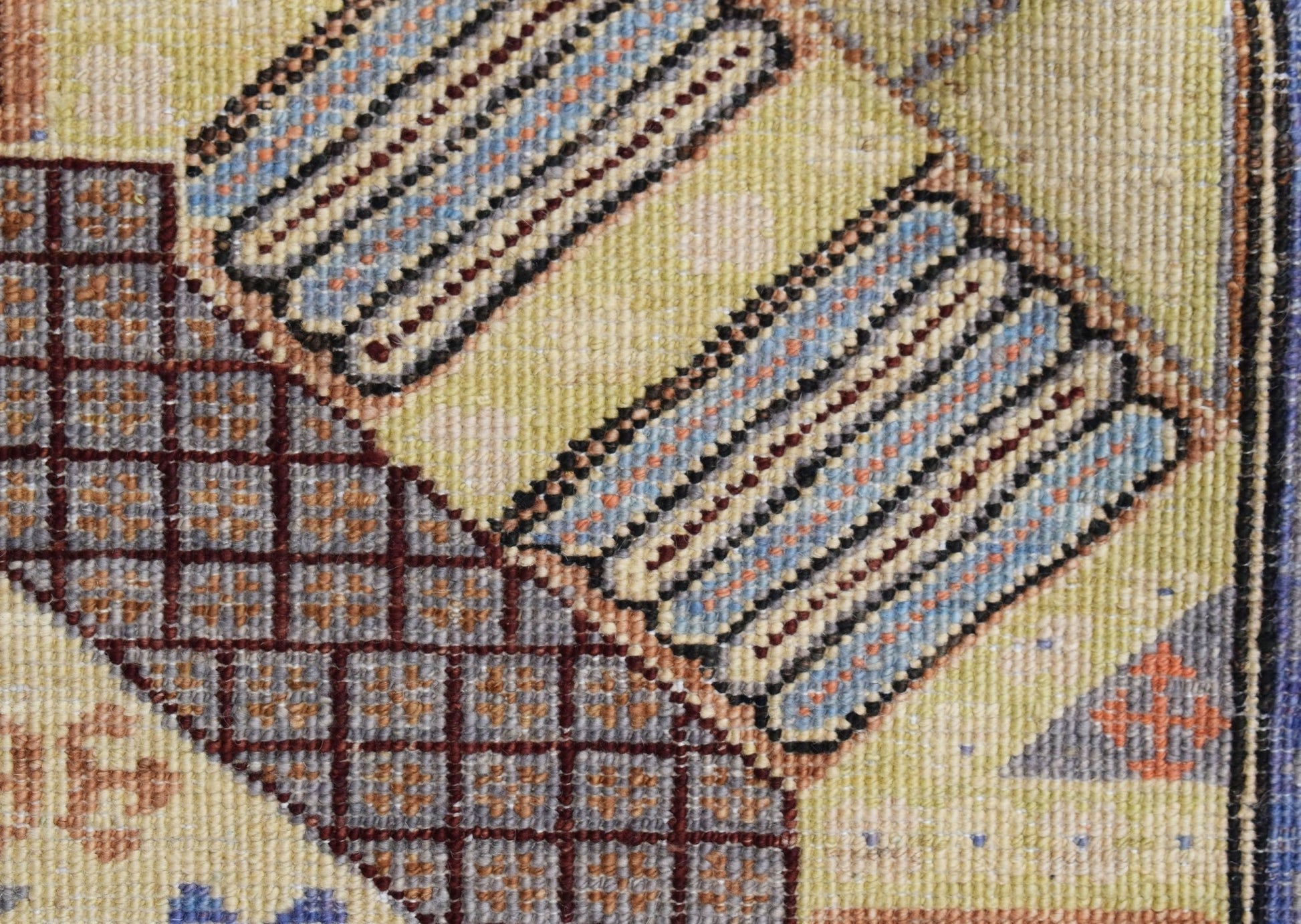A close-up of a handwoven Afghan Chobi runner featuring geometric patterns in blue, brown, and cream.