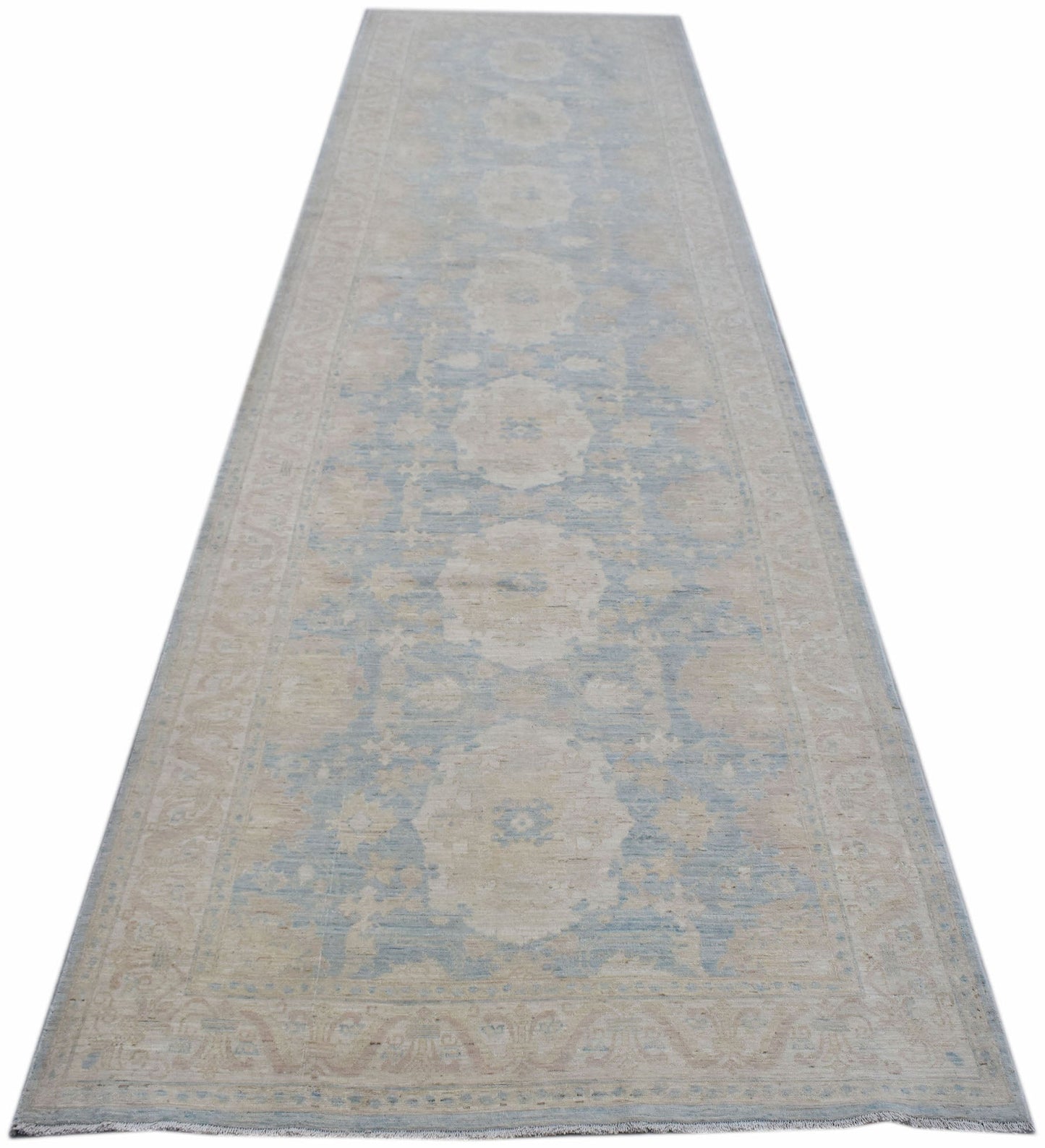 A long, handmade Afghan Chobi runner rug featuring a light blue and beige floral pattern.