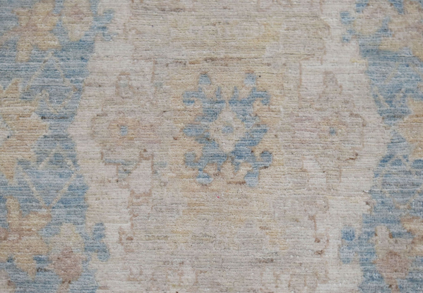 A close-up of an Afghan Chobi runner featuring a traditional floral pattern in blue and beige.
