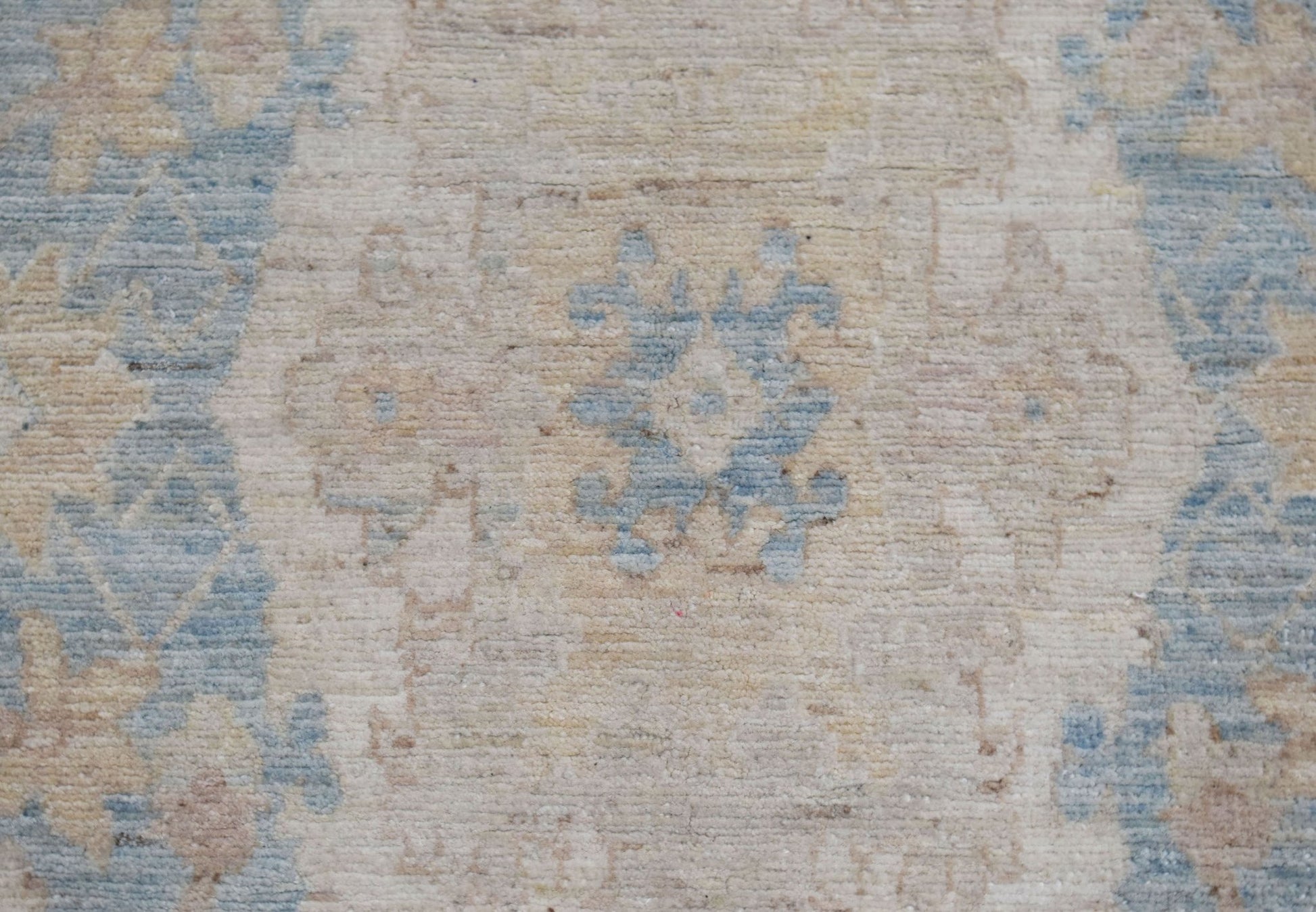 A close-up of an Afghan Chobi runner featuring a traditional floral pattern in blue and beige.