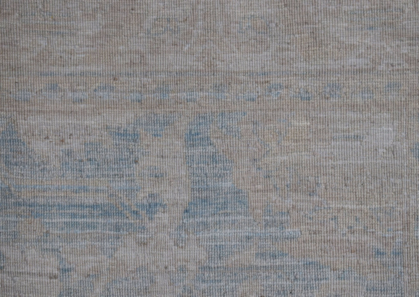 A handwoven Afghan Chobi runner featuring a subtle, distressed pattern in soft blue and beige.
