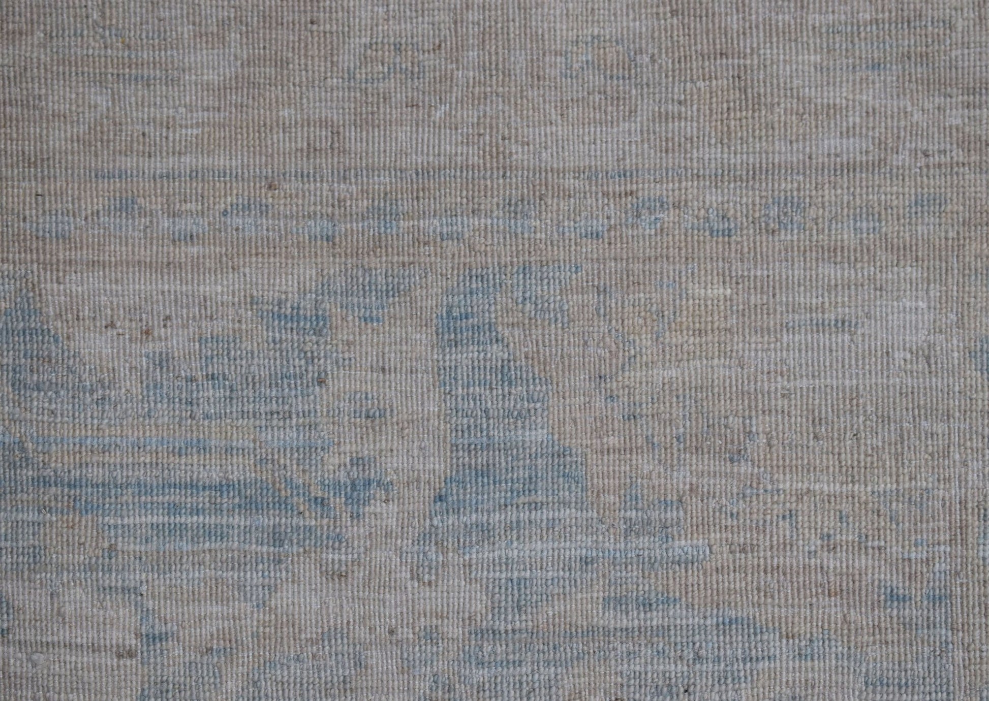 A handwoven Afghan Chobi runner featuring a subtle, distressed pattern in soft blue and beige.