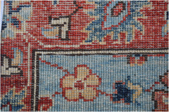 A close-up of an Afghan Chobi runner featuring traditional floral patterns in red and blue wool.
