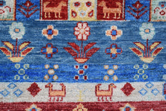 A handmade Afghan Chobi runner featuring stylized animal and floral motifs in blue and red tones.