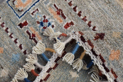 A close-up of a handmade Afghan Chobi runner featuring a wool pile and decorative knotted fringe.