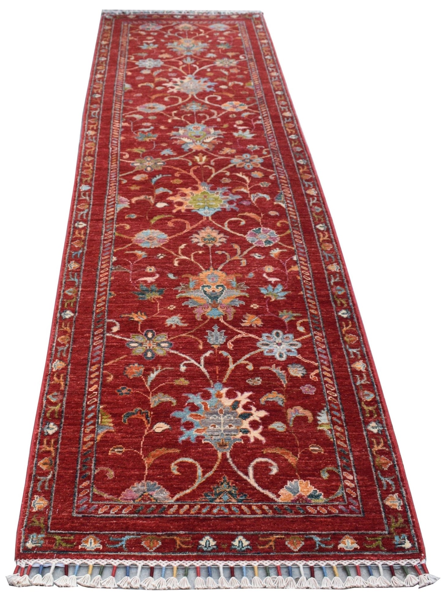 A handmade Afghan Chobi runner rug featuring a traditional floral pattern on a red background.