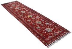 A handmade Afghan Chobi runner rug featuring a traditional floral pattern on a red background.