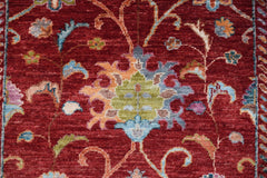 A handmade Afghan Chobi runner featuring a traditional floral pattern on a deep red background.