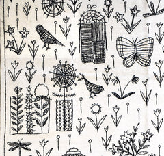 A handmade Afghan kilim featuring black embroidered botanical and animal motifs on a white base.