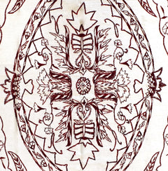 A close-up of an Afghan kilim featuring intricate dark red hand-embroidered floral motifs.