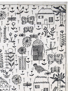 Handmade wool kilim featuring black embroidered folk art motifs of houses, butterflies, and plants.