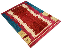 An Afghan Gabbeh rug featuring a bold geometric pattern in red, cream, and blue wool.