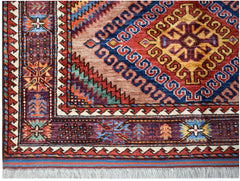 A handmade Afghan Herati rug featuring intricate geometric patterns in red, blue, and purple wool.