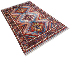 An Afghan Herati rug featuring a geometric diamond pattern in shades of red, blue, and tan.